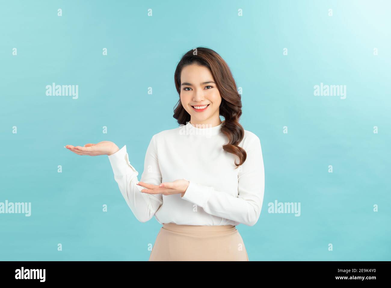Young attractive woman in casual wear shows her palm and smiling Stock Photo
