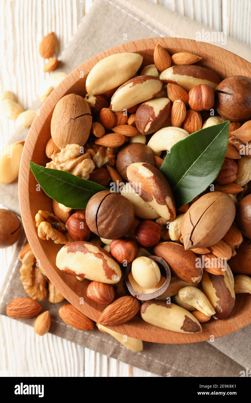 Bowl with different tasty nuts on white wooden background Stock Photo
