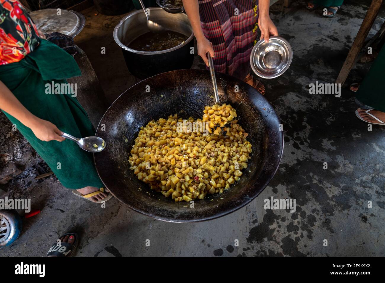 The students, most of whom are orphans who fled the civil war, come to their Chinpwi Education Boarding School in Myikyina, Myanmar, during their lunch break. The headmistress, Mai Wgi Lathe, distributes the food from the large cooking pots. Stock Photo