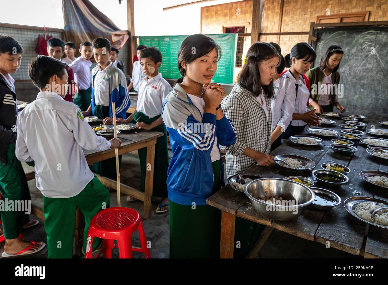The students, most of whom are orphans who fled the civil war, come to their Chinpwi Education Boarding School in Myikyina, Myanmar, during their lunch break. The headmistress, Mai Wgi Lathe, distributes the food from the large cooking pots. Stock Photo