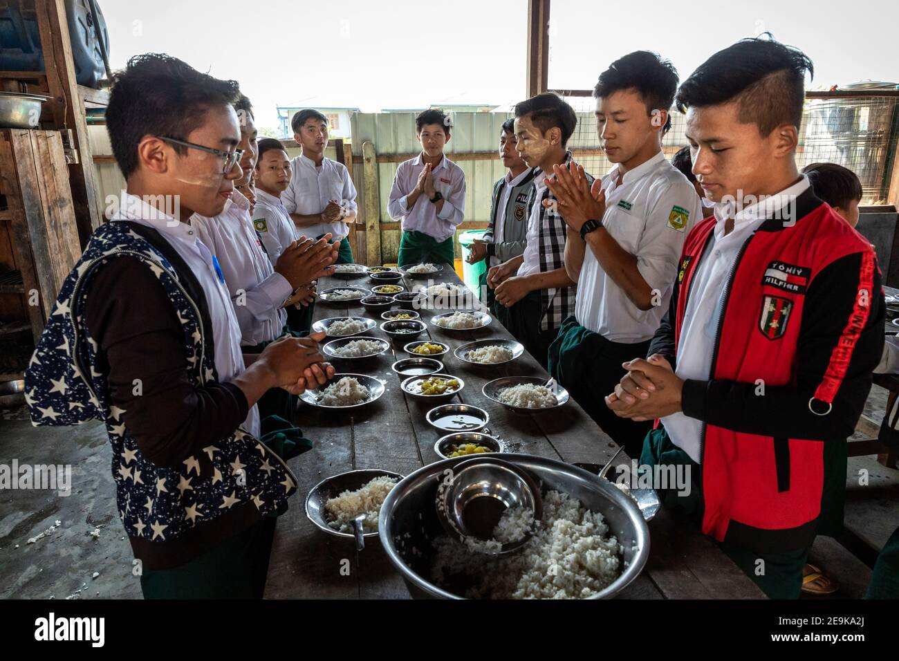 The students, most of whom are orphans who fled the civil war, come to their Chinpwi Education Boarding School in Myikyina, Myanmar, during their lunch break. The headmistress, Mai Wgi Lathe, distributes the food from the large cooking pots. Stock Photo