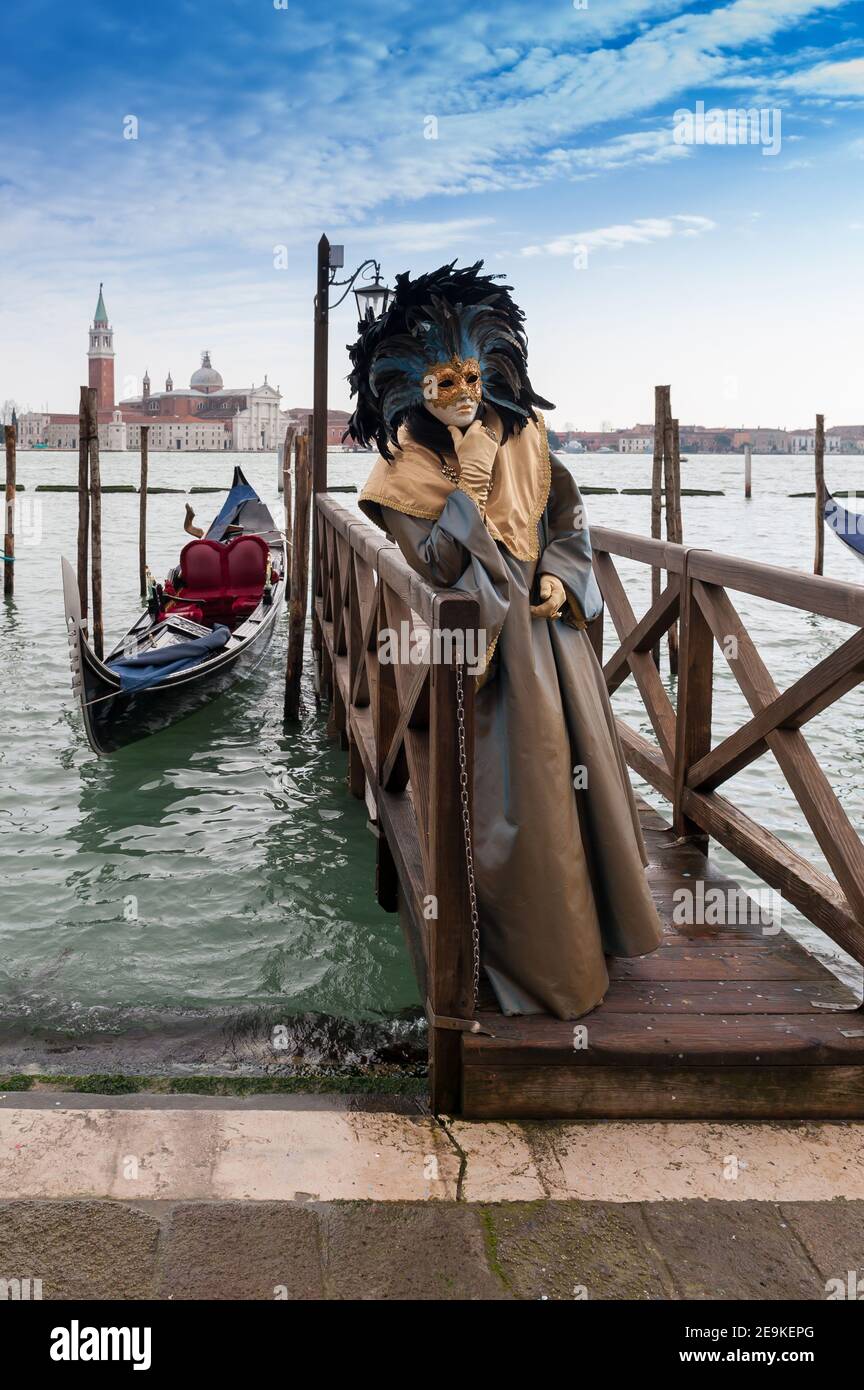 Venice carnival figure in front of the lagoon and the island of San Giorgio Maggiore in Venice, Veneto, Italy Stock Photo