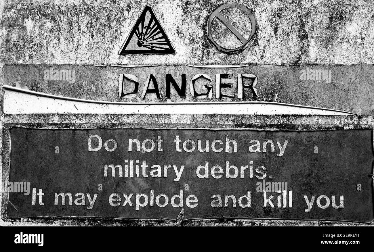 Weathered sign warning of danger of military debris that could explode. Stock Photo