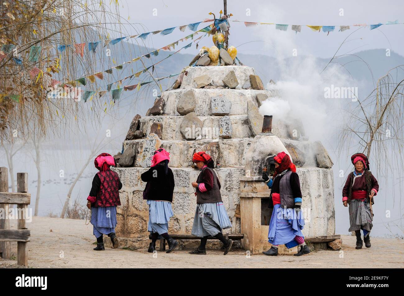 CHINA, province Yunnan, Xialuoshui, ethnic minority Mosuo who are buddhist and women exercise a matriarchy, old Mosuo women with prayer mills go around a buddhist shrine at Lugu Lake / CHINA, Provinz Yunnan, ethnische Minderheit Mosuo , die Mosuo sind Buddhisten und Mosuo Frauen ueben ein Matriarchat aus, Frauen mit Gebetsmuehlen umrunden einen Schrein am Lugu See Stock Photo