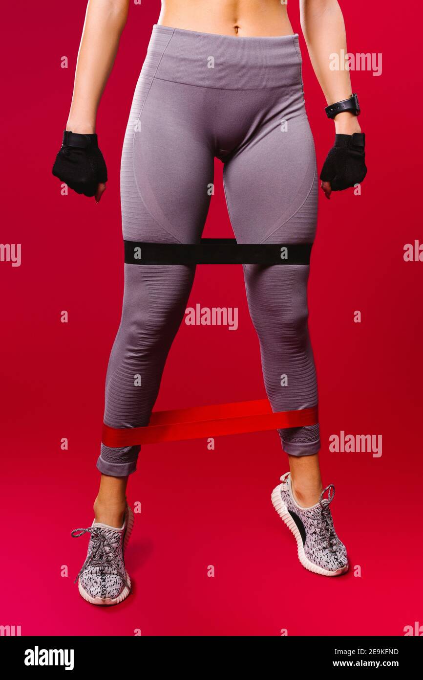 Women's muscular legs in leggings with an elastic band on a red
