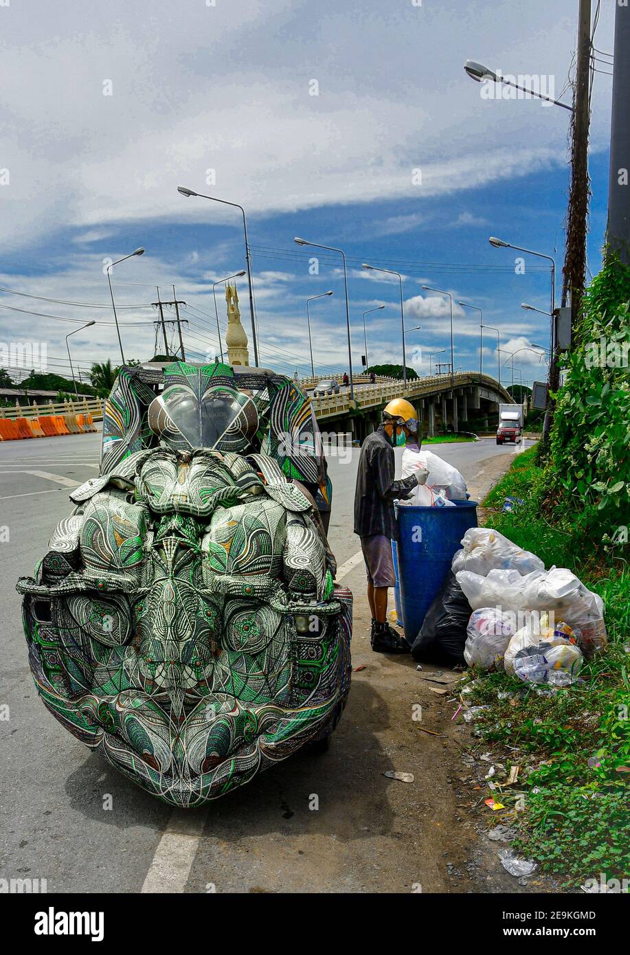 Old asian man rummaging through a refuse bin, collecting recyclable