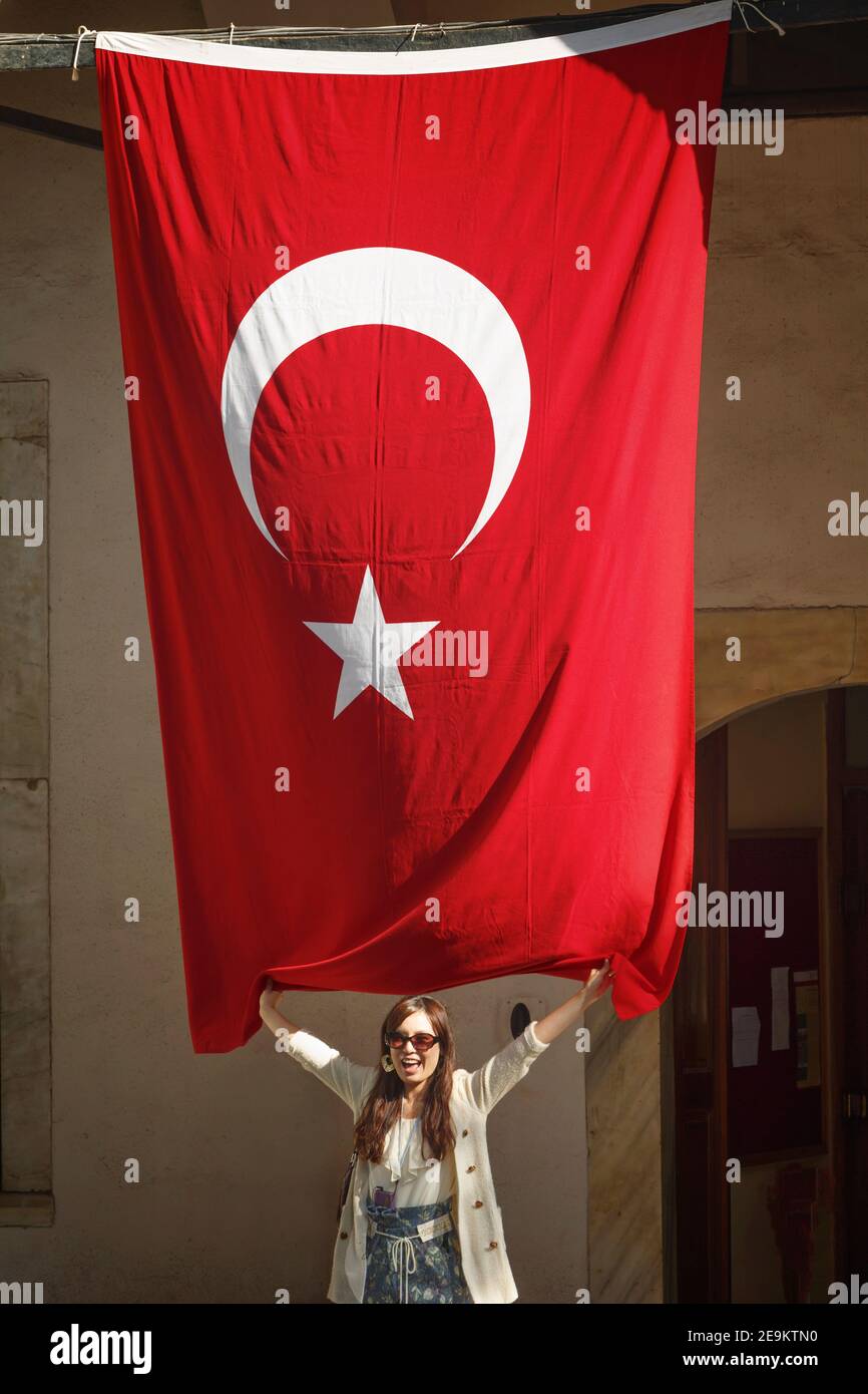 Istanbul, Turkey.  Topkapi Palace. Topkapi Sarayi. Young tourist posing with Turkish national flag.  Topkapi is part of the Historic Areas of Istanbul Stock Photo