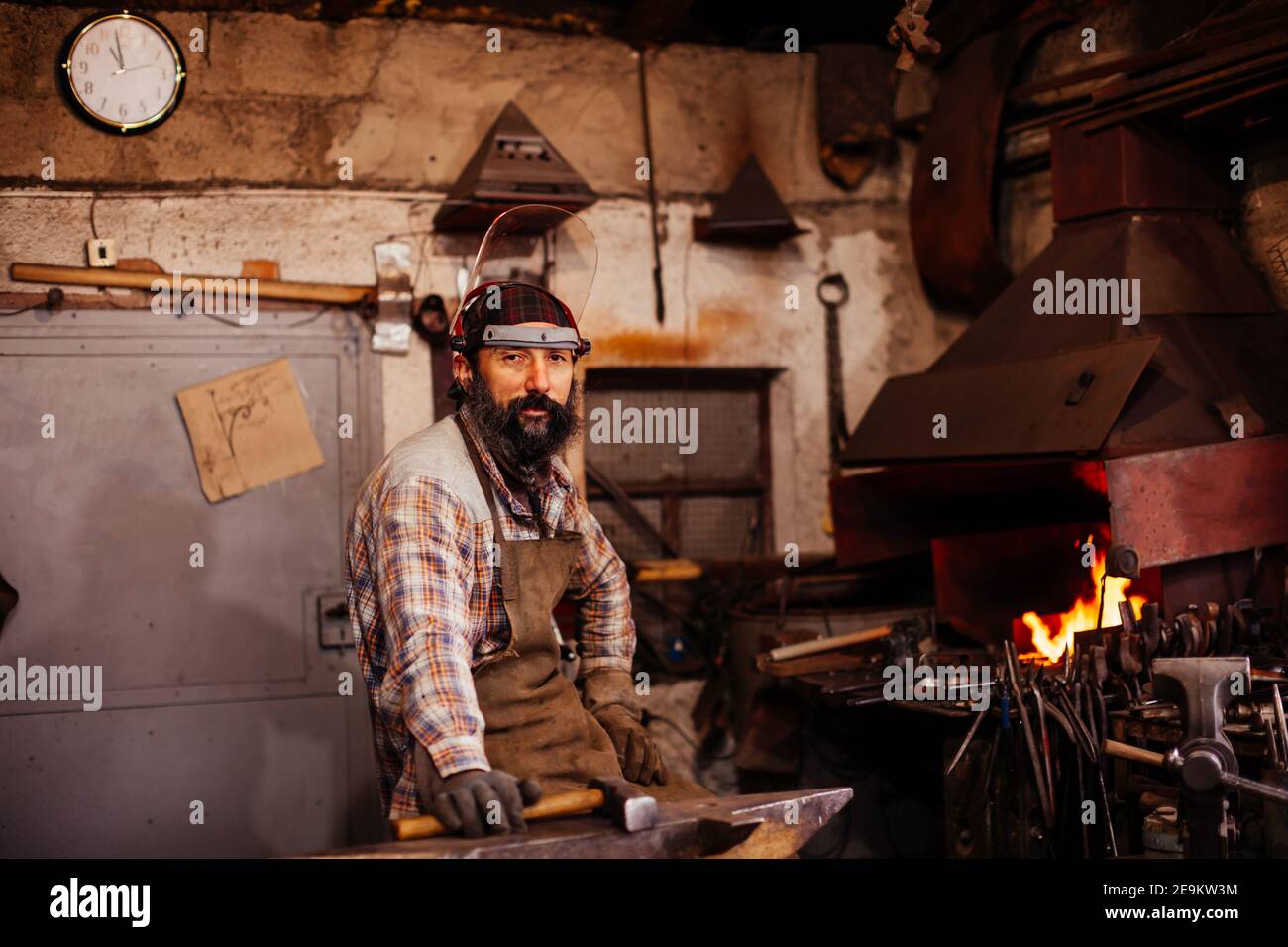 Bearded blacksmith after working in his workshop. Blacksmith's workshop. Stock Photo