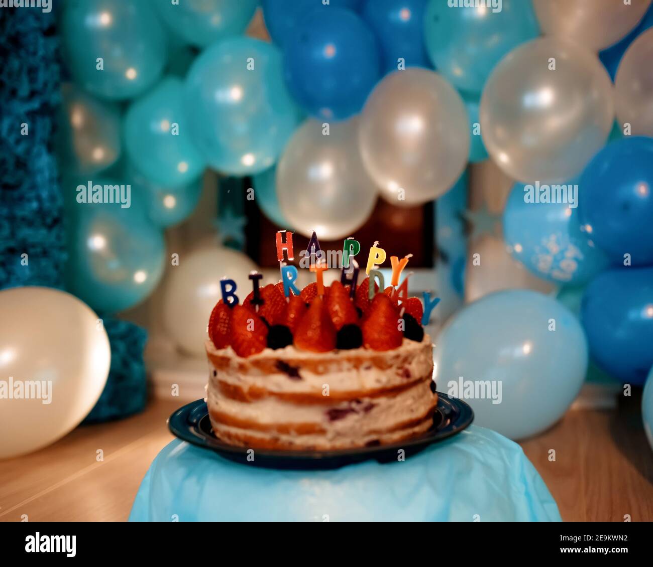 birthday cake with candles against blue balloons Stock Photo - Alamy