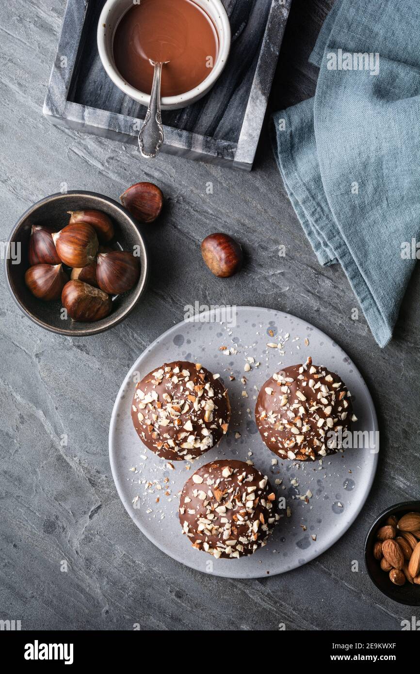 Sweet chestnut cups filled with soft curd cheese, chestnut puree and ground almonds, topped with chocolate frosting and chopped nuts on stone backgrou Stock Photo
