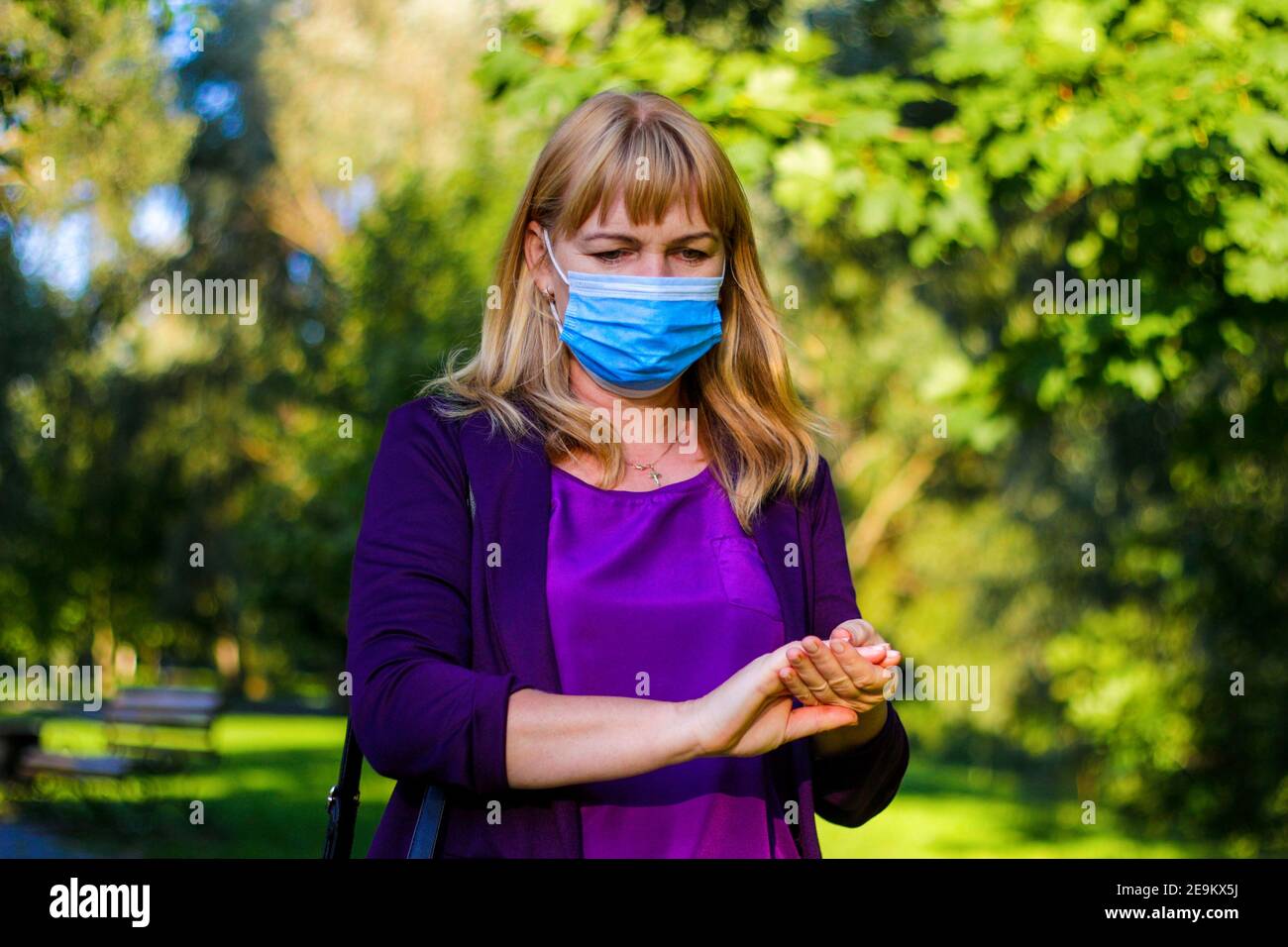 Woman wearing blue antivirus mask rubbing her hands with sanitizer. .Women rubs her hands using a sanitizer spray. The concept of hygiene and Stock Photo