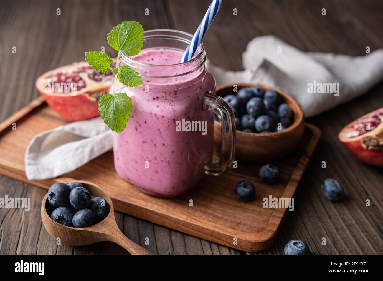 Pomegranate and blueberry smoothie mixed with yogurt and almond milk, served in a glass jar on rustic wooden background Stock Photo