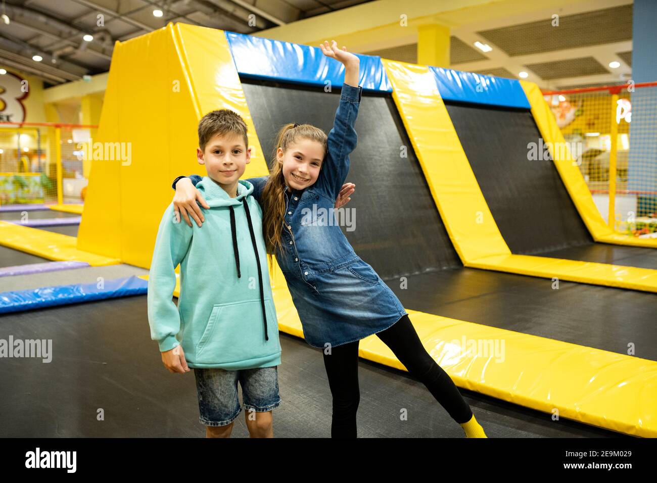 Cute twin brother and sister jumping and bouncing on indoor trampoline ...