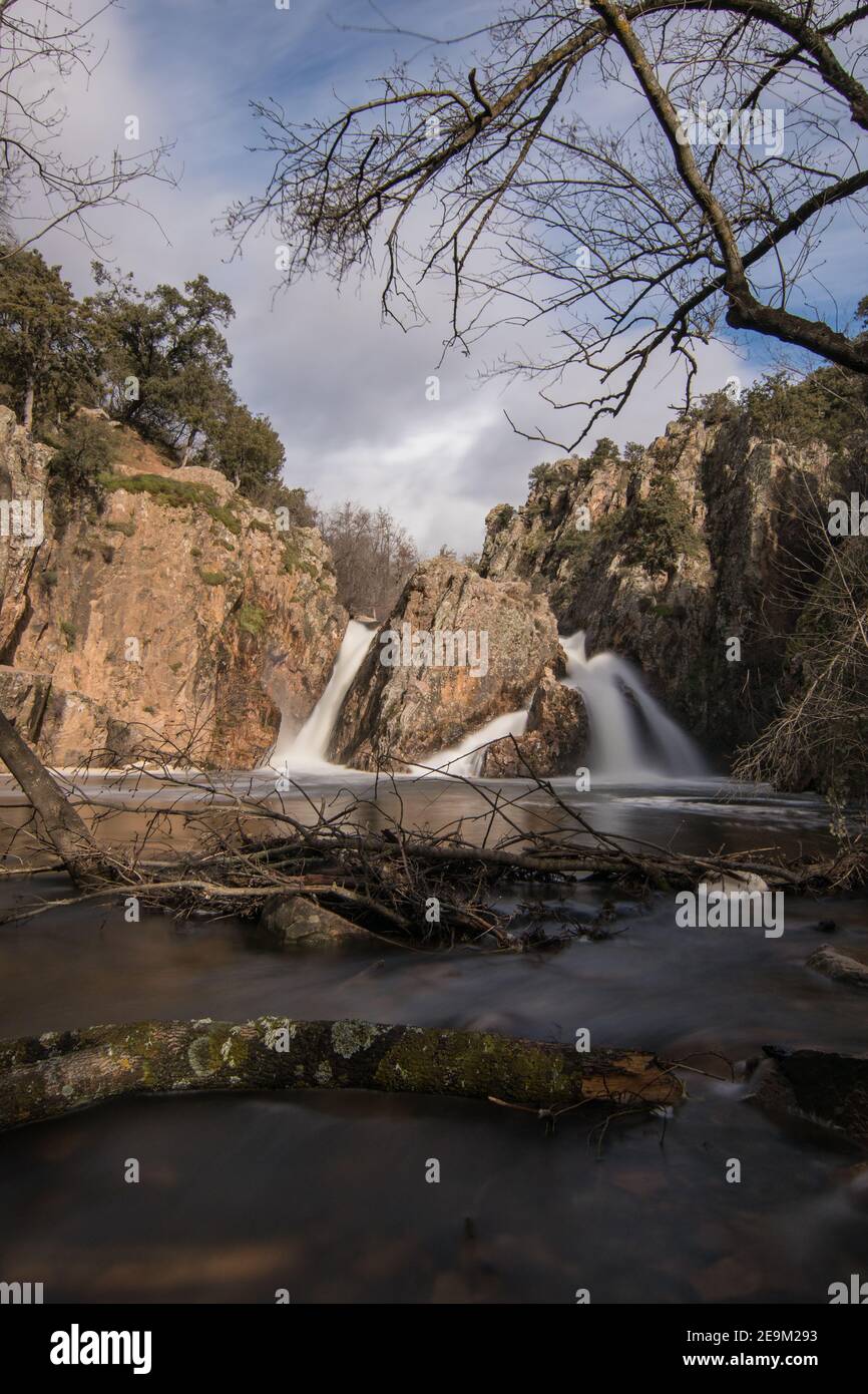 Vertical shot of a waterfall with long exposure surrounded by rocks ...