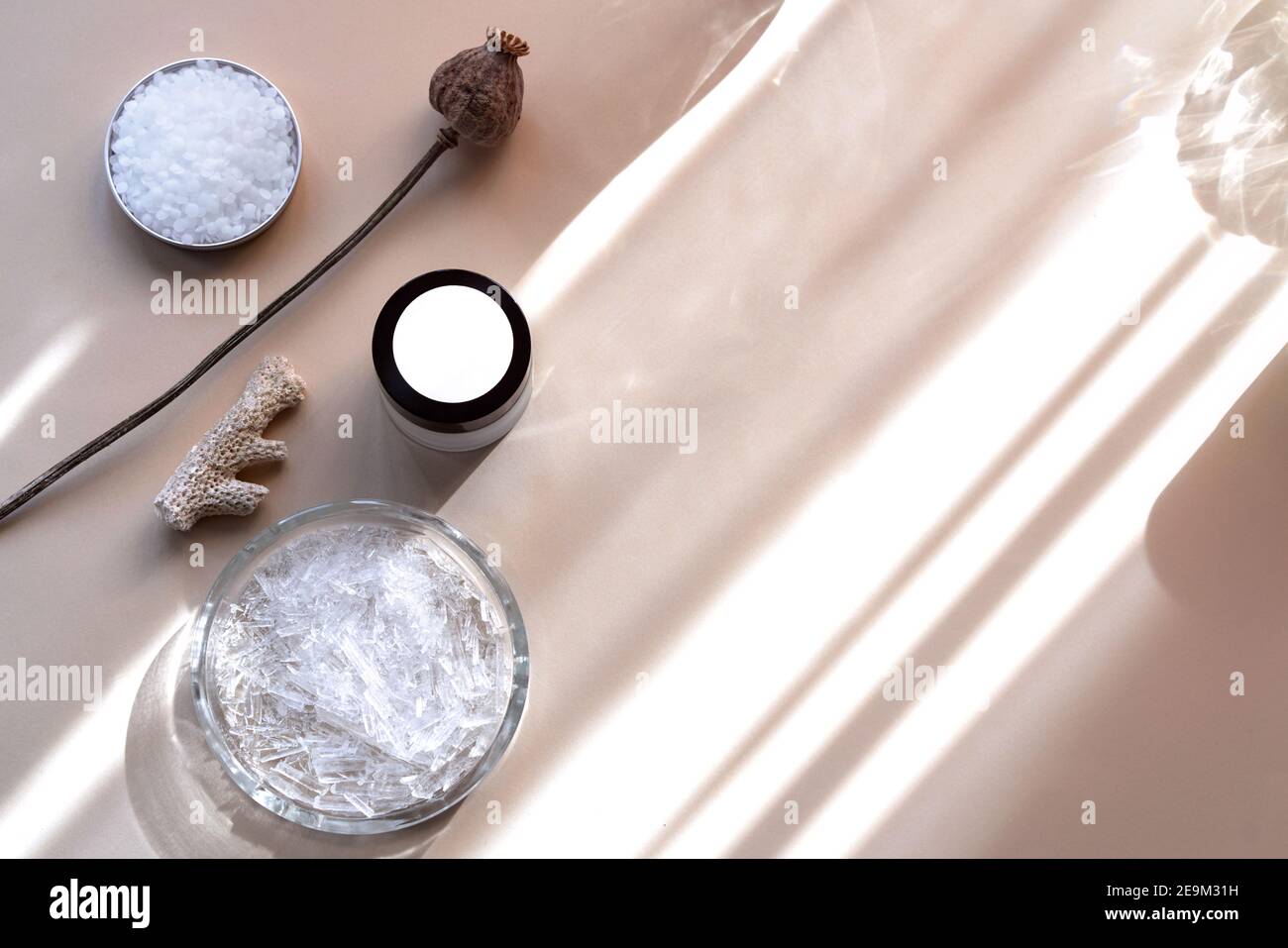 Ingredients for the production of cosmetics on a beige background with sun glare. Clays, wax