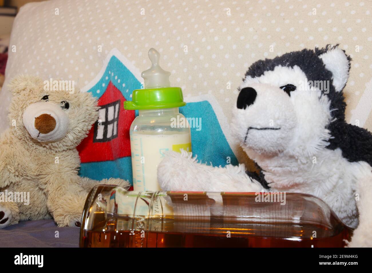 Symbol image of alcohol addiction in parents: cuddly toys, baby bottle and alcohol Stock Photo