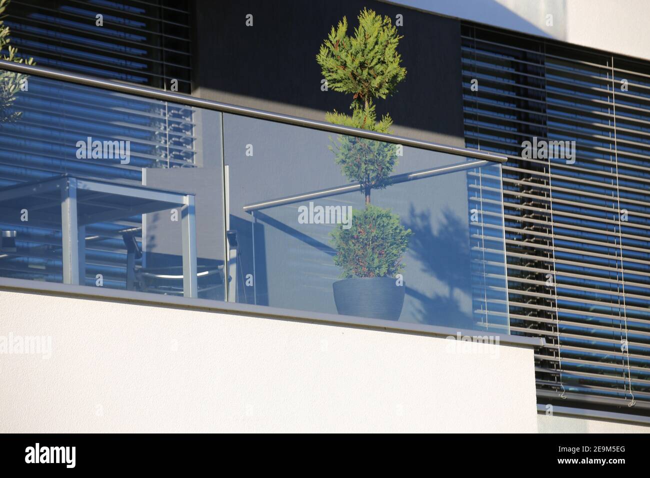 Balcony railings made of glass and stainless steel, behind them windows ...