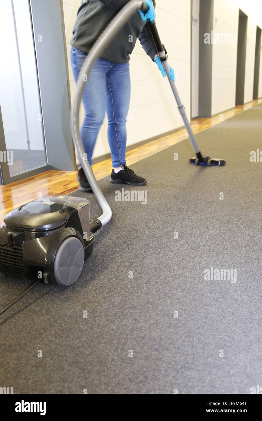 Office cleaning Cleaner vacuums the corridor of an office Stock Photo