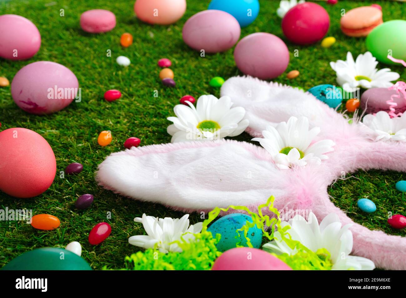 Colored eggs and vibrant candies on grass. Easter composition Stock Photo