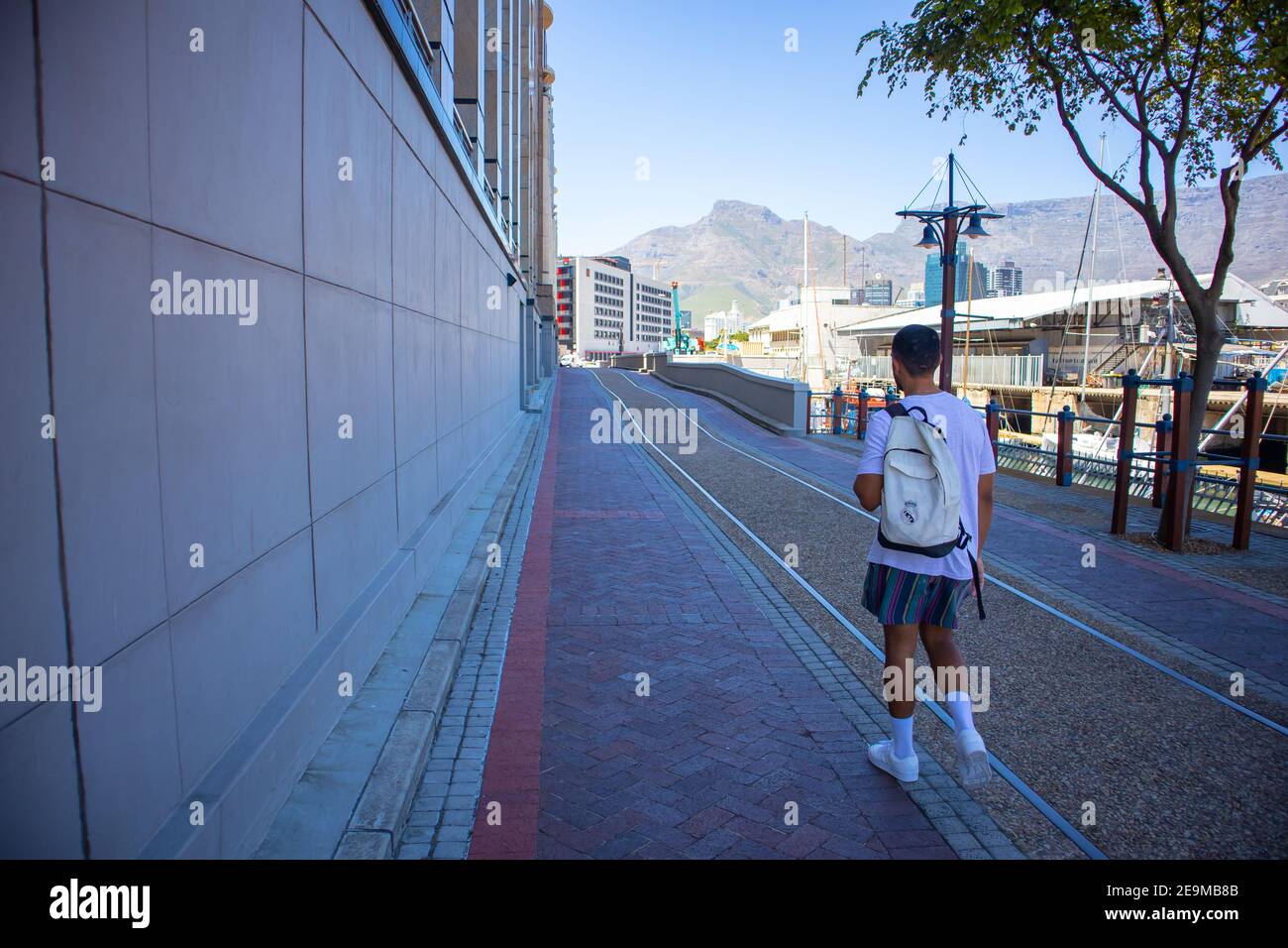 Waterfront- Cape Town, South Africa - 03-02-2021 Shady side road leading to Silo District at the Waterfront. Stylish man walking by in foreground. Stock Photo