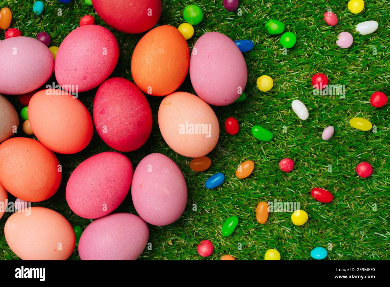 Colored eggs and vibrant candies on grass. Easter composition Stock Photo