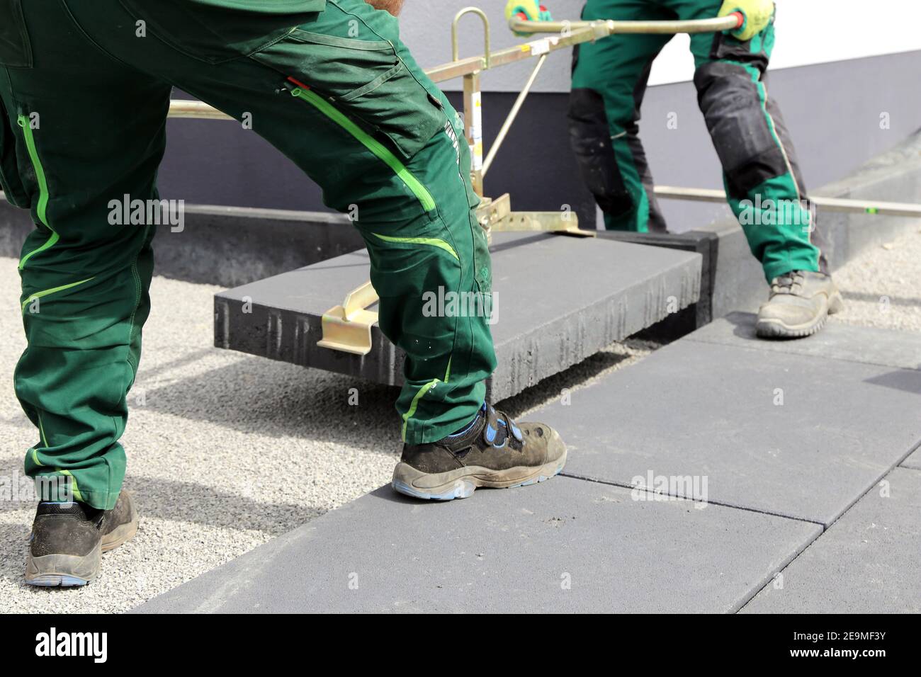 Construction workers lay heavy paving stones with a stone lifter Stock Photo