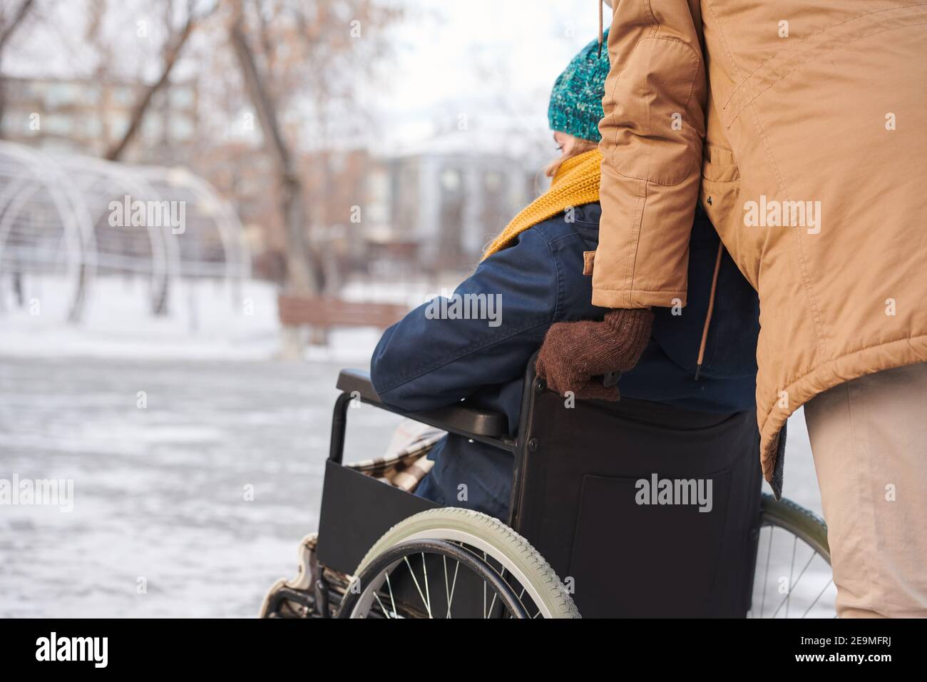 Rear view of disabled woman walking in the park in winter with her ...