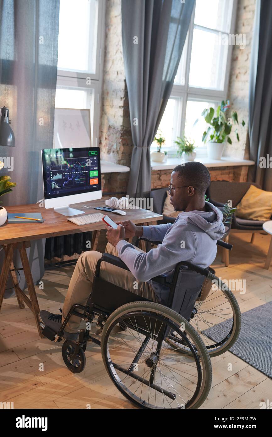 Disabled designer working online at home sitting at his workplace in