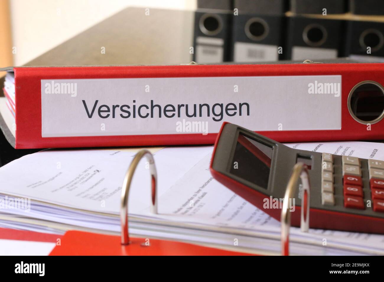 Symbol image: Folder with insurance policies and calculator on a desk (german) Stock Photo