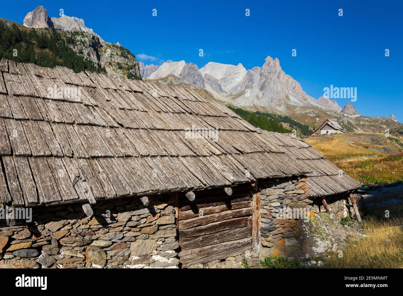 Typical chalet of stones and wood planks roof. Vallée de la Clarée. Pointe des Cerces and Roches de Crépin. Névache. Hautes Alpes. France. Europe Stock Photo