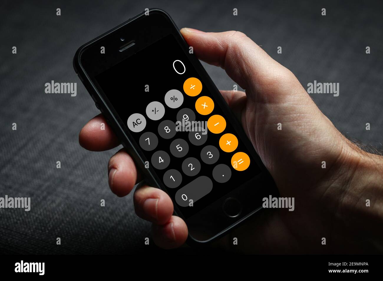 a man using the iPhone calculator on his iPhone Stock Photo