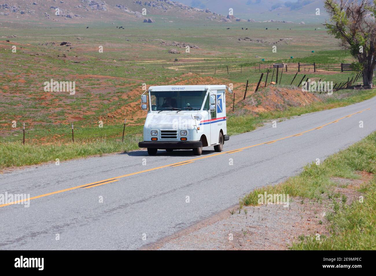 CALIFORNIA, UNITED STATES - APRIL 12, 2014: Postman drives US Postal Service van in remote rural area of Tulare County, California. USPS is the only d Stock Photo