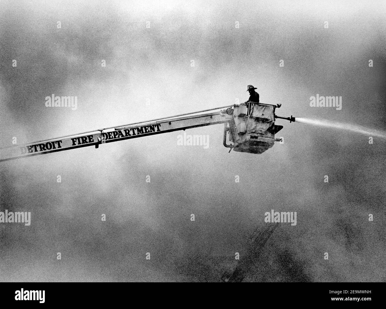 Black & white image of firefighter directing water on fire from hydraulic aerial platform on Detroit Fire Department truck Stock Photo