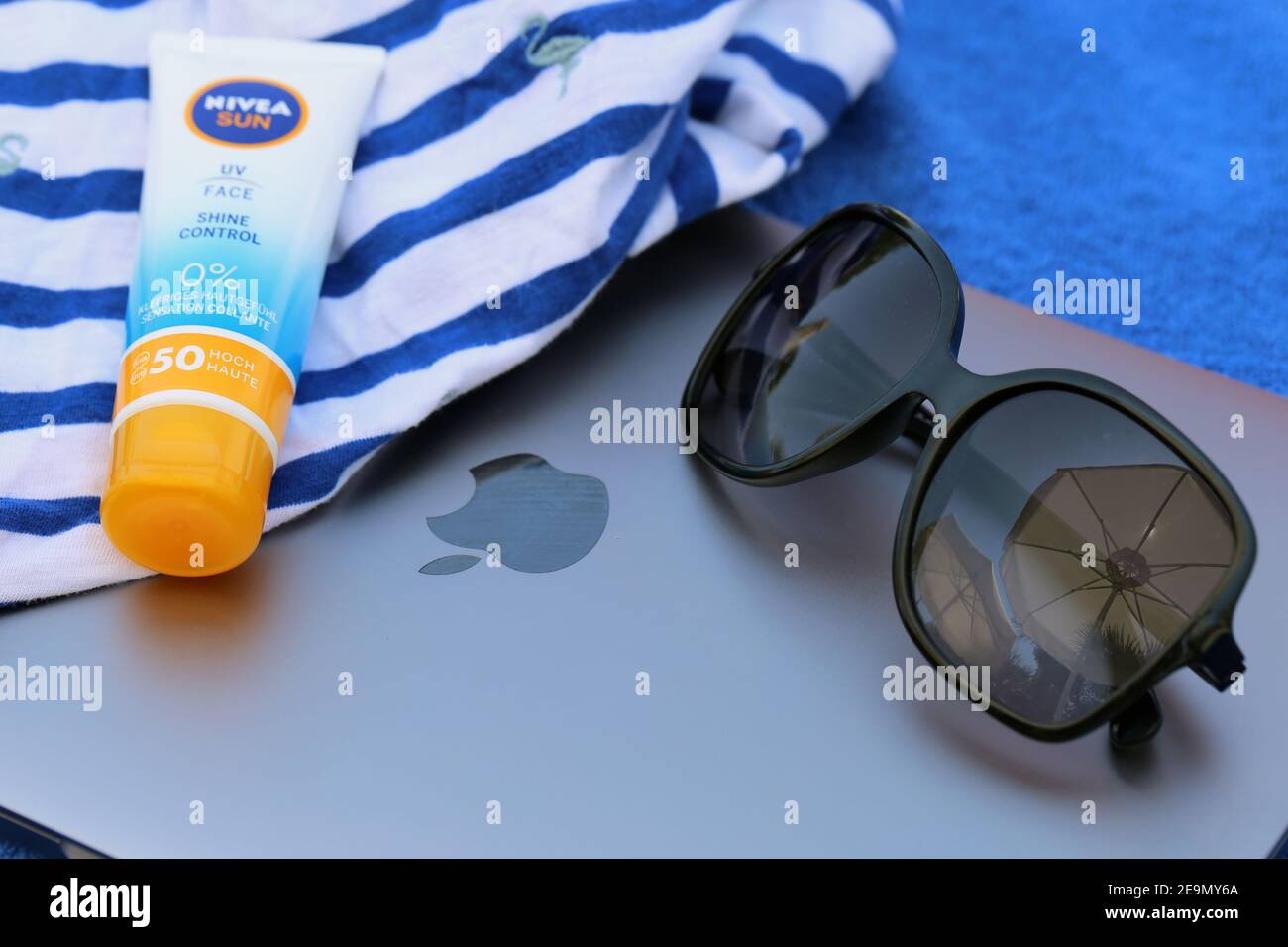 Sun block bottle, Dolce and Gabbana sunglasses, MacBook, beach shirt and  beach towel in a closeup photo. White, blue and orange colors. Cyprus Aug  19 Stock Photo - Alamy