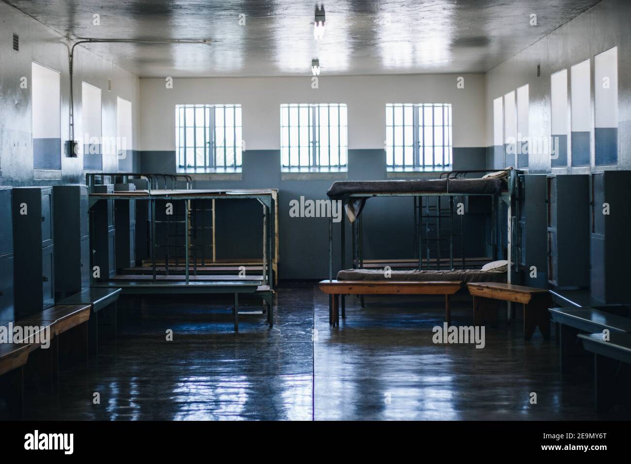 Perfectly clean prison cell metal bunk beds, sitting benches, and wall
