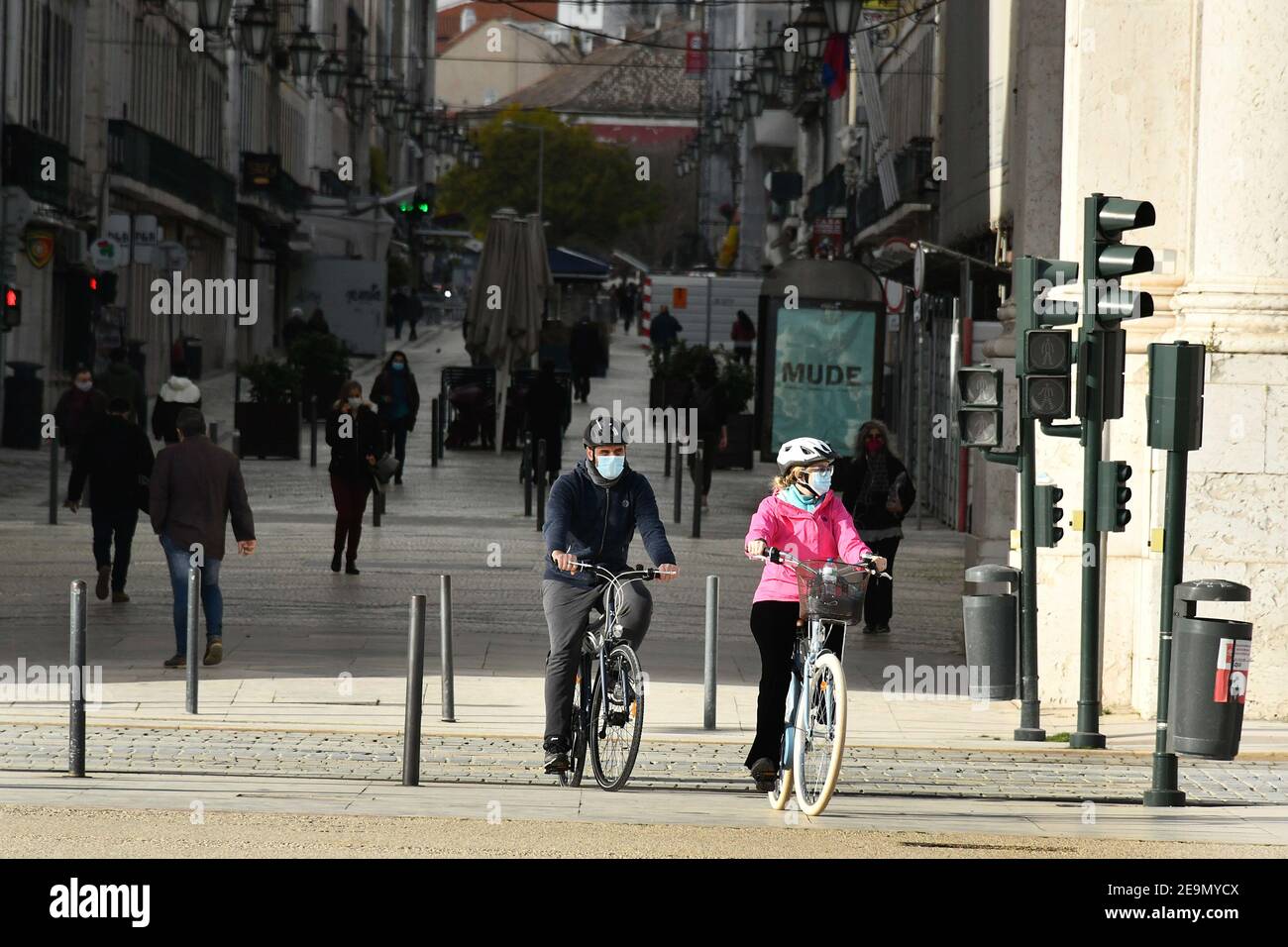 Two people wearing face masks ride bicycles near Praça de Comercio in Lisbon. Portugal has registered 13,740 deaths and 755,774 confirmed cases since the beginning of the pandemic according to the bulletin of the General Health Department (DGS). Stock Photo