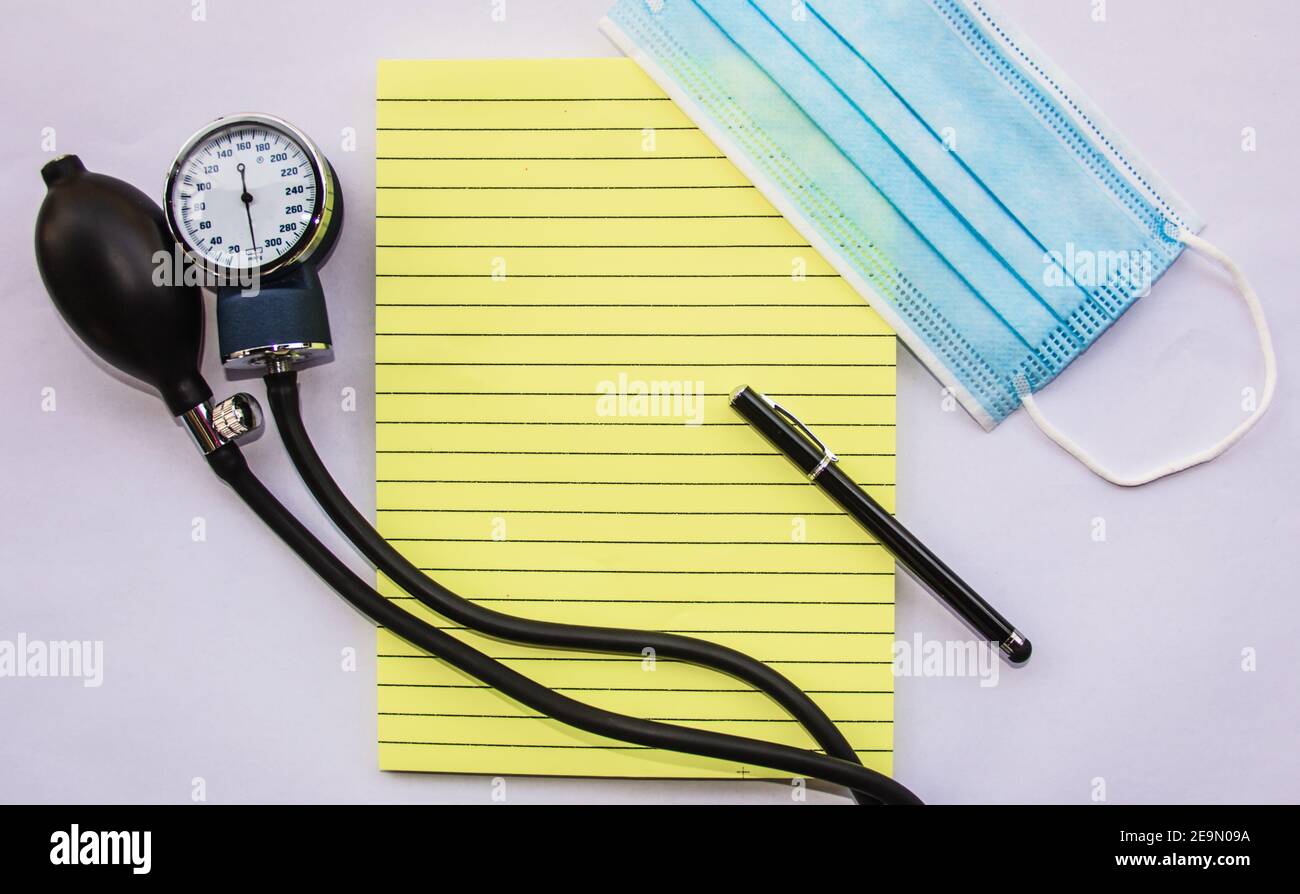 medical blue mask with notepad and manual blood pressure reader representing work of doctors Stock Photo