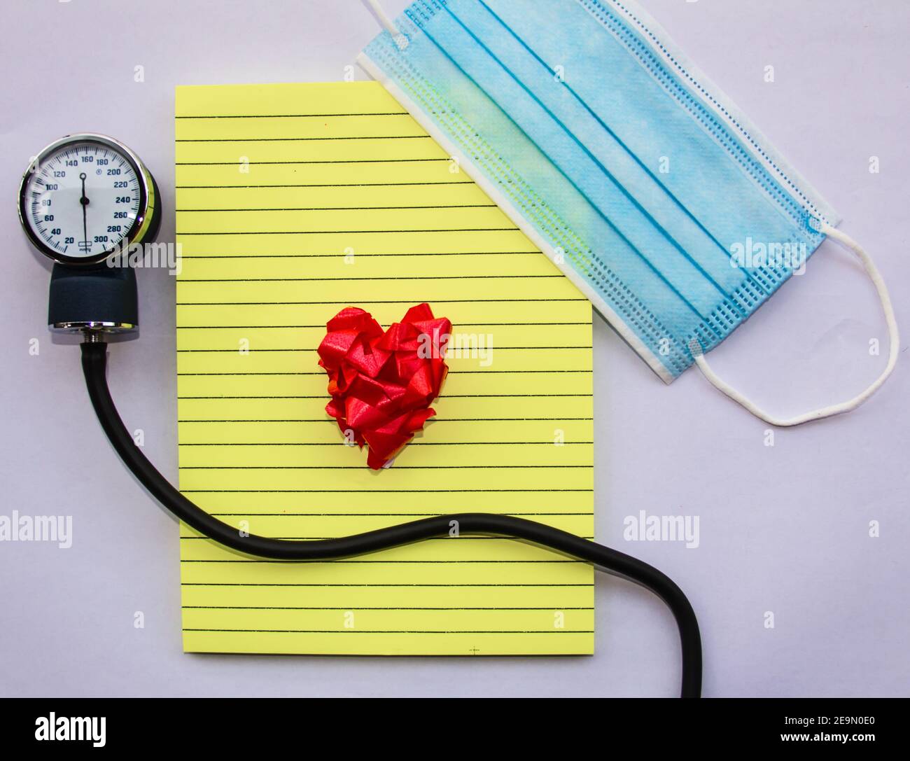 concept love medical blue mask with notepad and manual blood pressure reader and a ribbon heart representing love for doctors Stock Photo