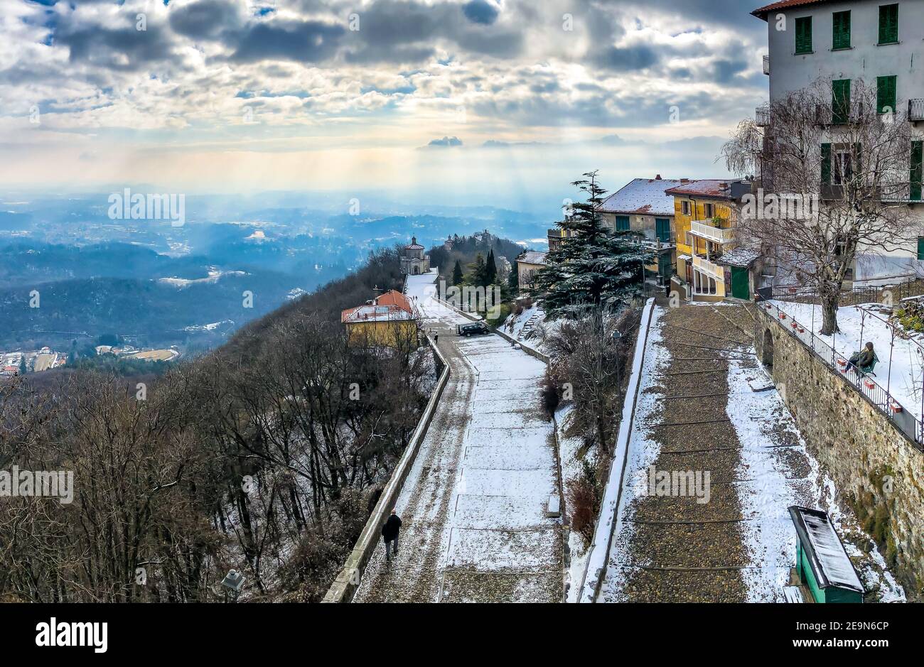 View from Sacred Mount or Sacro Monte of Varese on the historic pilgrimage route with Chapel XIV and sun rays in background in a winter cloudy day, Va Stock Photo