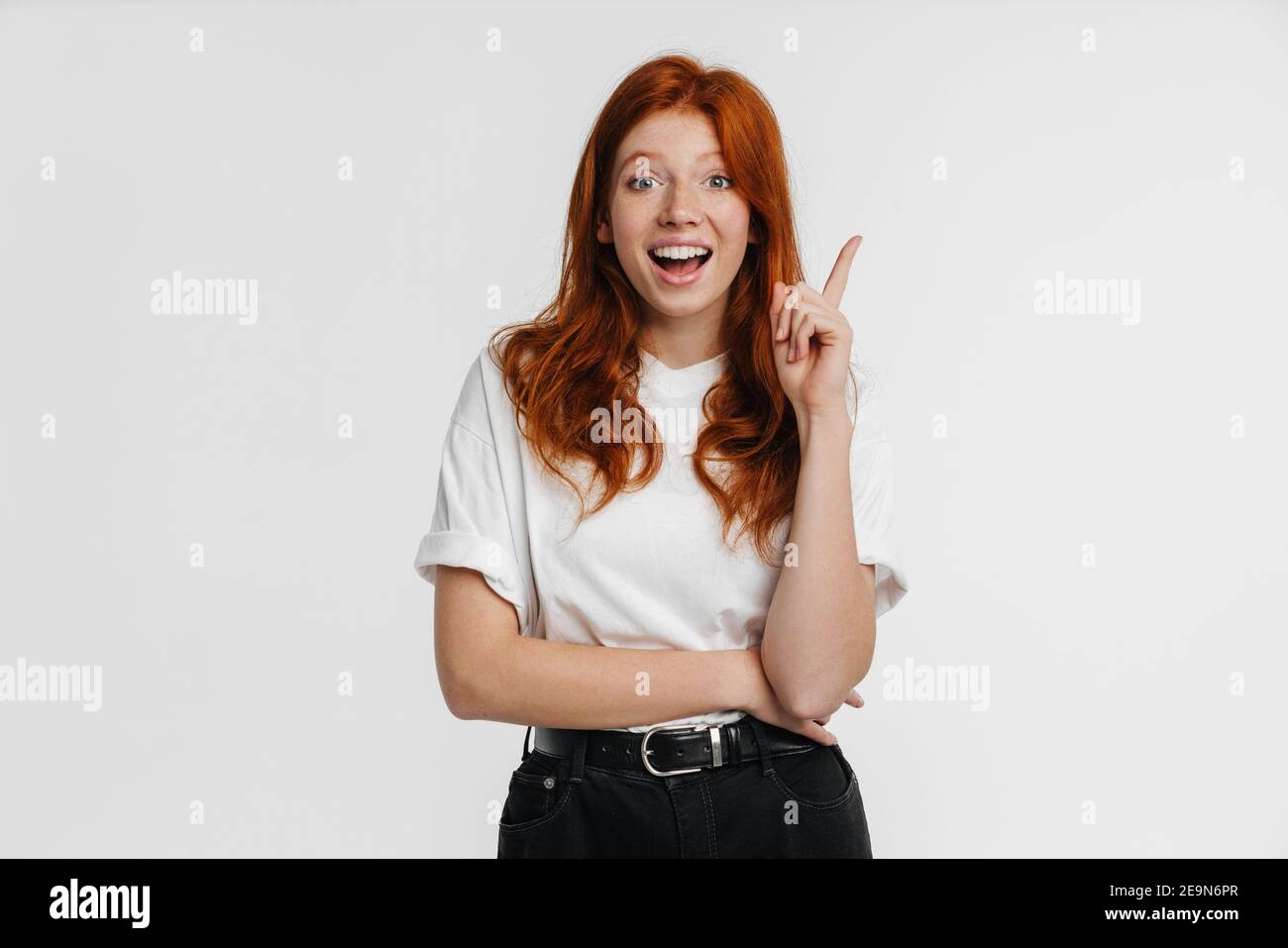 Ginger beautiful excited girl exclaiming and pointing finger upward ...