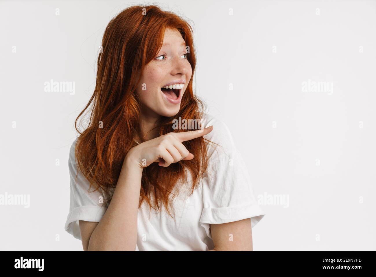 Ginger beautiful excited girl smiling and pointing finger aside ...