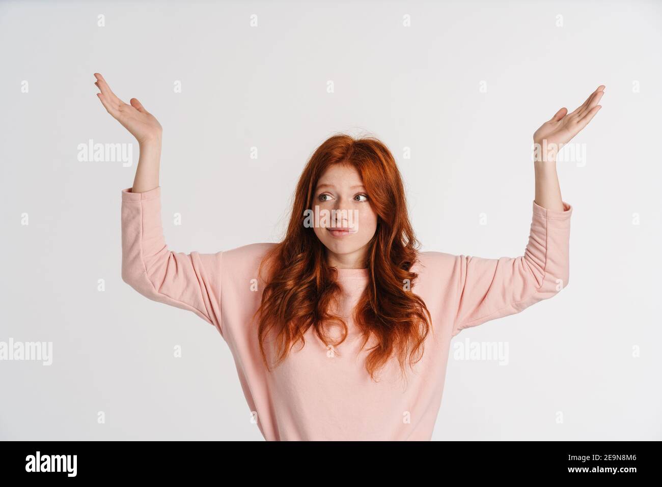 Ginger beautiful confused girl posing and holding copyspace isolated ...