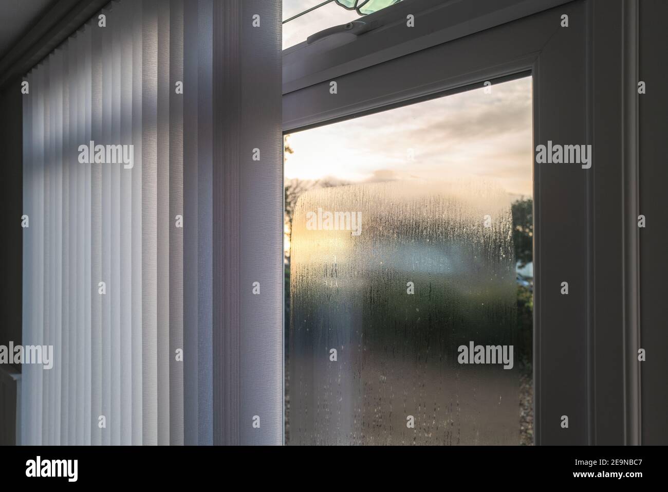 Condensation on the outside of double glazed window glass at sunrise. The window has vertical