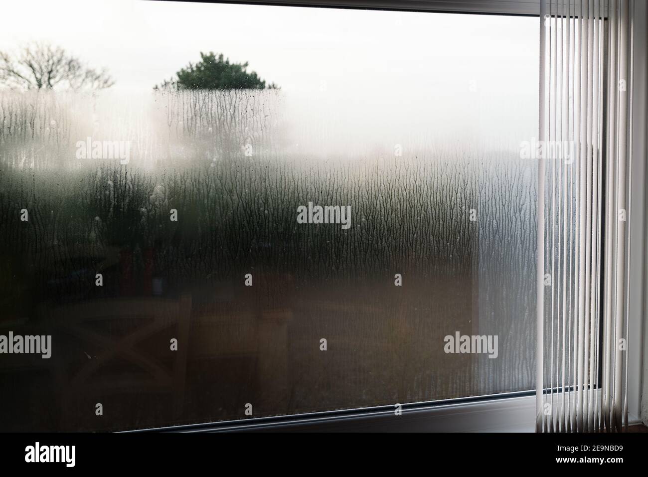 Condensation on the outside of double glazed window glass at sunrise. The window has vertical