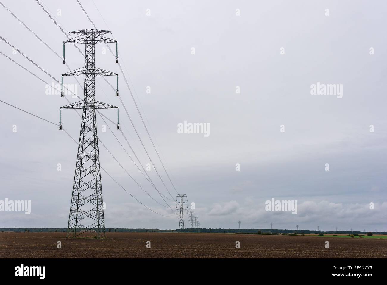 Extra-high voltage 400 kV overhead power line on large pylons, used for long distance, very high power transmission. Cloudy sky and copy space Stock Photo