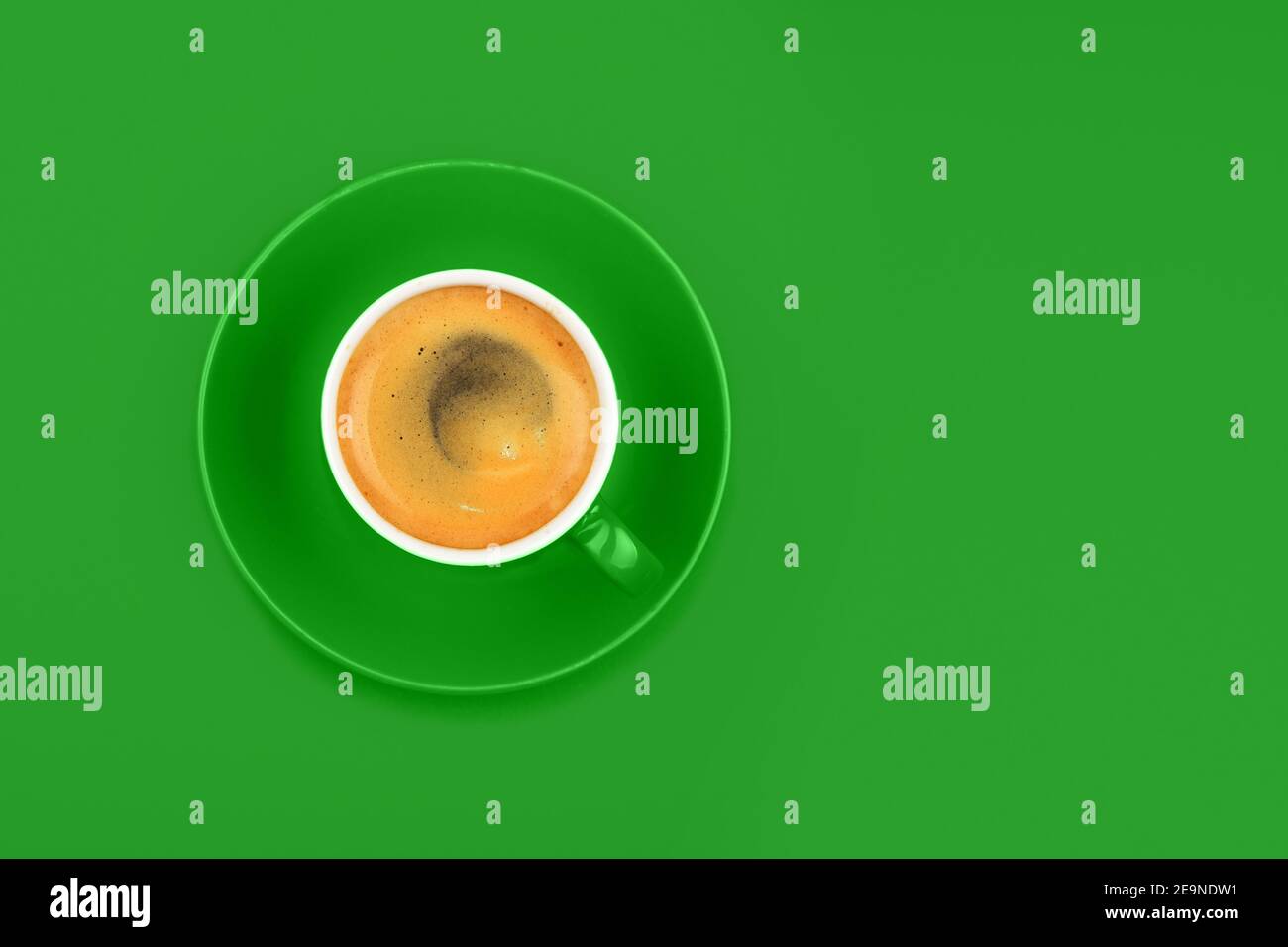 One full espresso coffee cup with saucer over vivid green paper ...