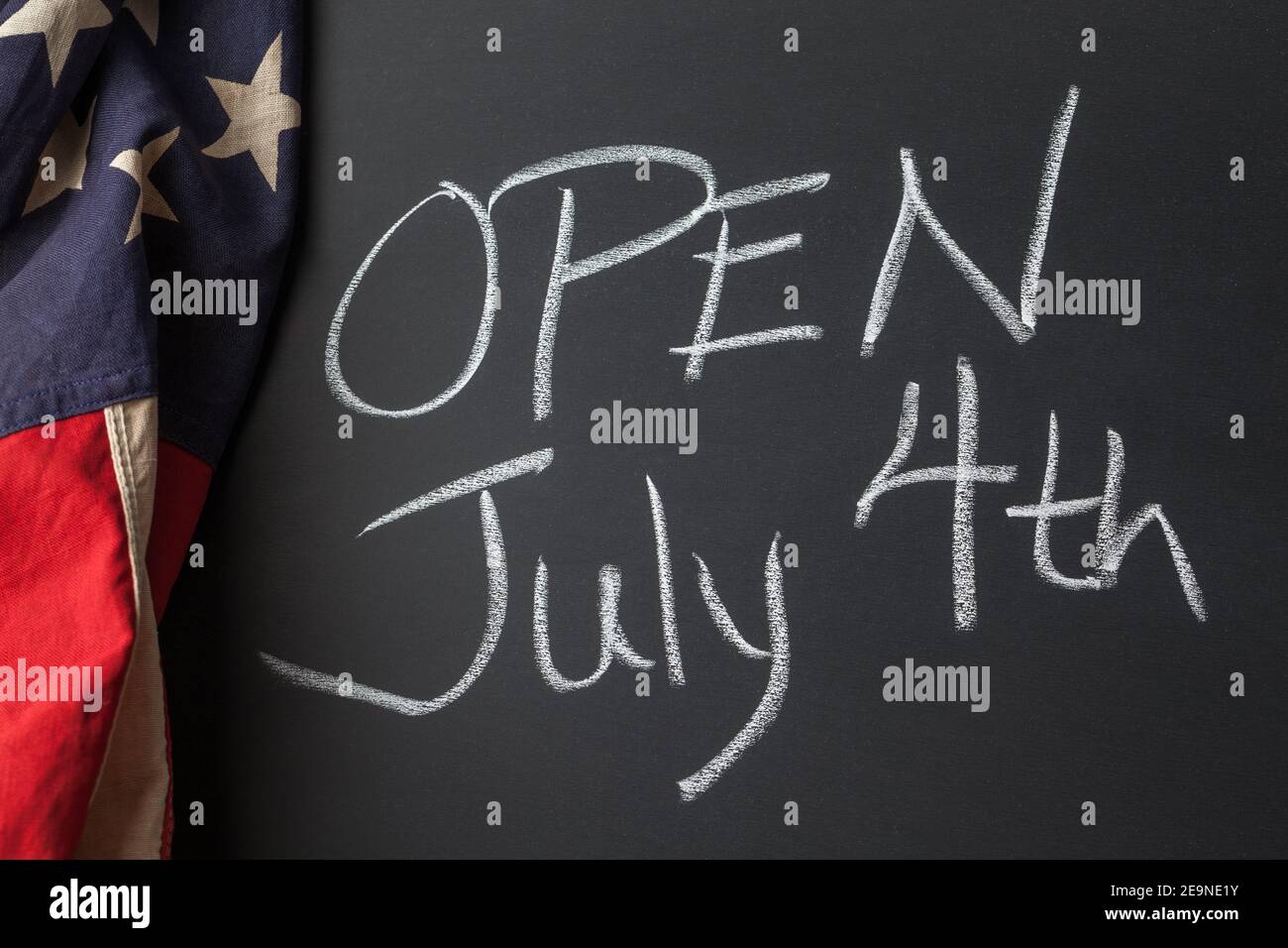 Open July 4th sign handwritten on a chalkboard bordered by a vintage American flag Stock Photo