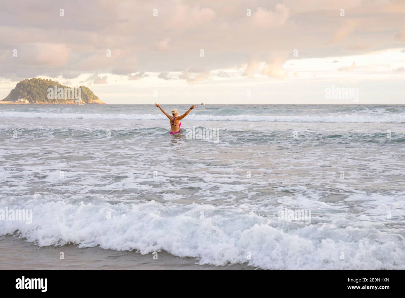 Europe, Spain, Gipuzkoa, Zarautz Beach with older woman bathing at dawn Stock Photo