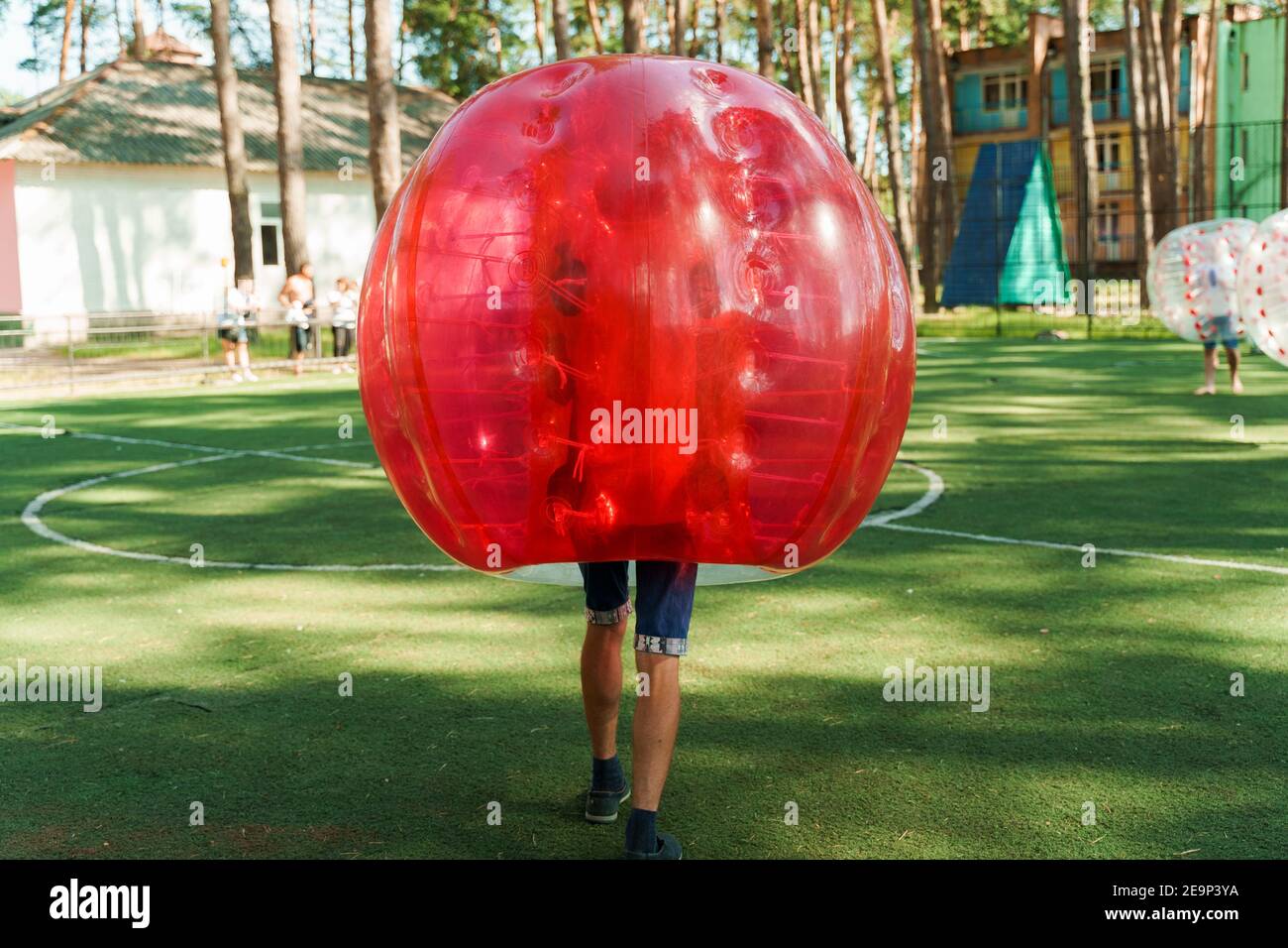 Bubble football sport game. Football players play bumperball on the green field. Team building