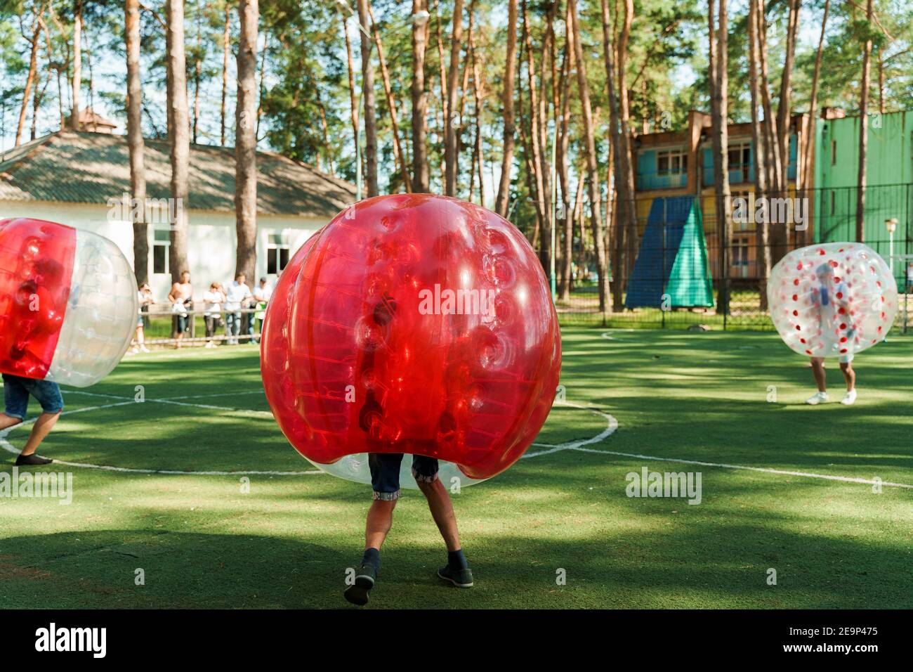 Bubble football sport game. Football players play bumperball on the green field. Team building